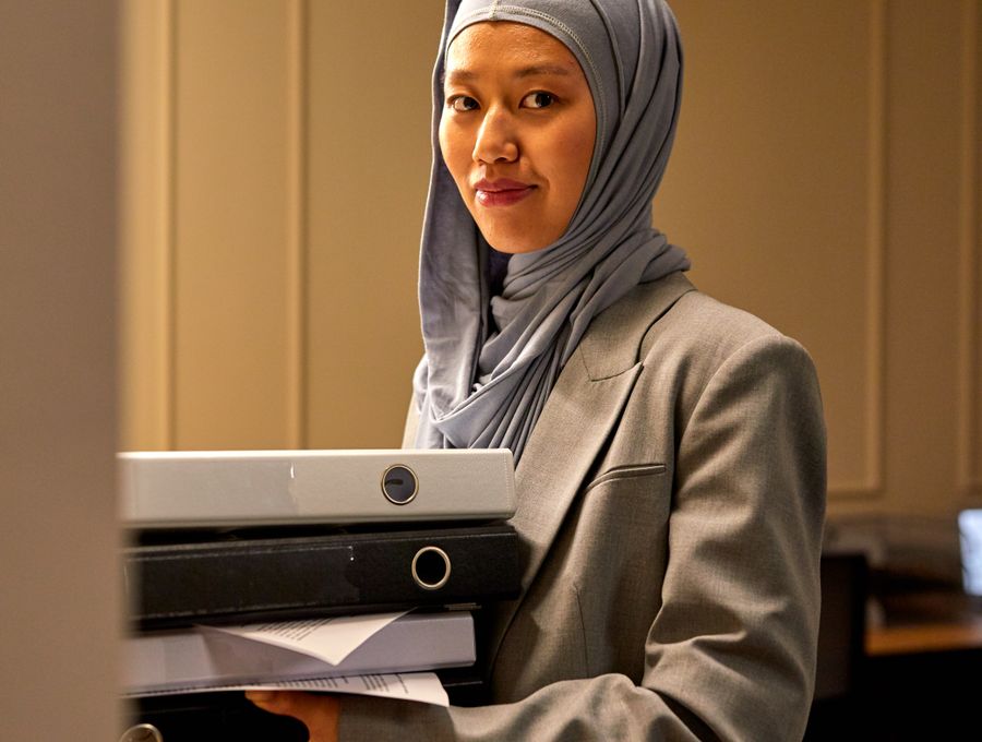 A businesswoman carrying files in her office